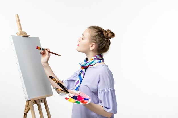 Vista frontal de la pintora preparándose para dibujar en la pared blanca artista caballete dibujo pintura lápiz