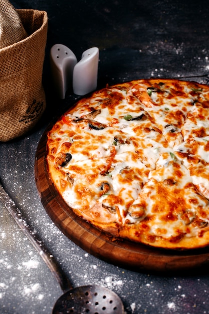 Vista frontal de pizza con queso en el piso gris