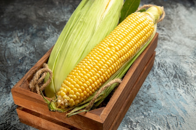 Vista frontal de la planta amarilla de maíz crudo fresco dentro de la caja sobre fondo oscuro-claro