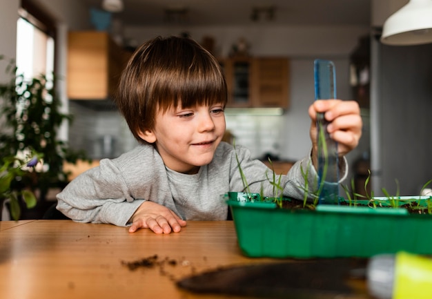 Vista frontal de la planta de medición de niño sonriente que crece en casa