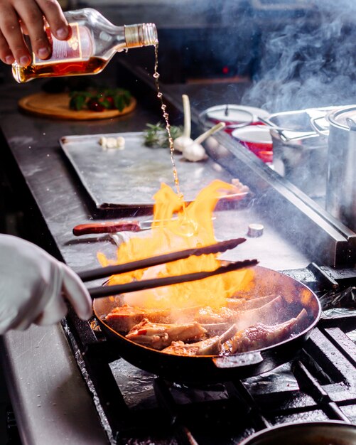 Vista frontal plato cocina freír carne dentro de una sartén redonda en la cocina