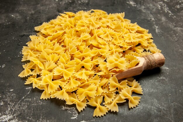 Vista frontal poca pasta cruda en color gris oscuro foto de color de alimentos muchas masas de pasta italiana