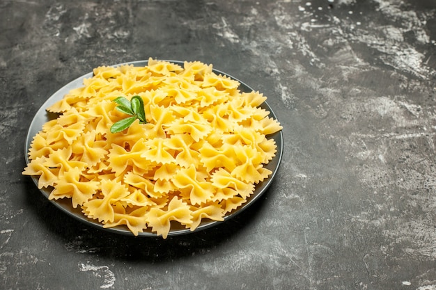 Vista frontal poco de pasta cruda dentro de la placa en color gris oscuro comida de comida de comida de pasta italiana color