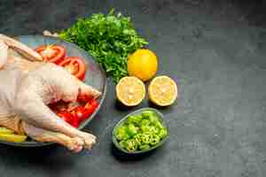 Foto gratuita vista frontal de pollo crudo fresco dentro de la placa con verduras de limón y verduras sobre fondo oscuro color de los alimentos carne animal de pollo