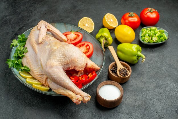 Vista frontal de pollo crudo fresco con verduras de limón y verduras sobre fondo oscuro comida de aves color carne foto animal