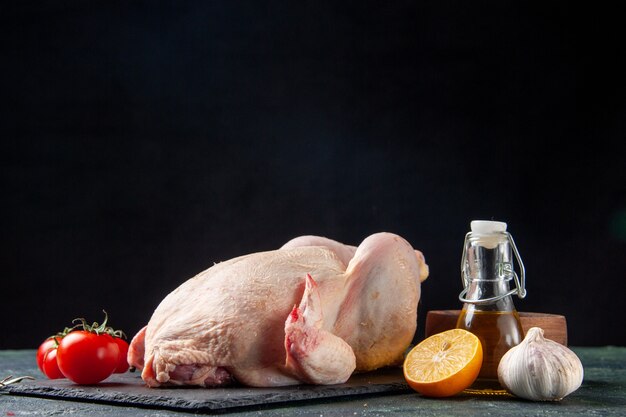 Vista frontal de pollo fresco con tomates rojos en la cocina oscura comida de restaurante foto de animales comida de color de carne pollo