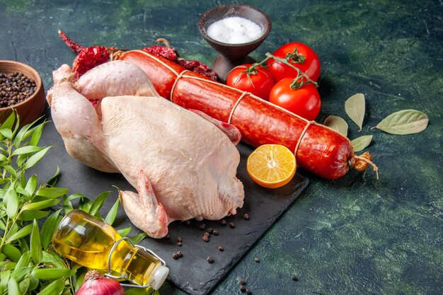 Vista frontal de pollo fresco con tomates y salchichas en la cocina oscura comida de restaurante comida de fotografía animal color de carne de pollo