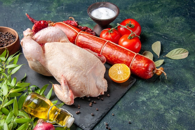 Vista frontal de pollo fresco con tomates y salchichas en la cocina oscura comida de restaurante comida de fotografía animal color de carne de pollo