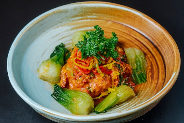 Vista frontal de pollo frito en salsa con puerro y hierbas en un plato