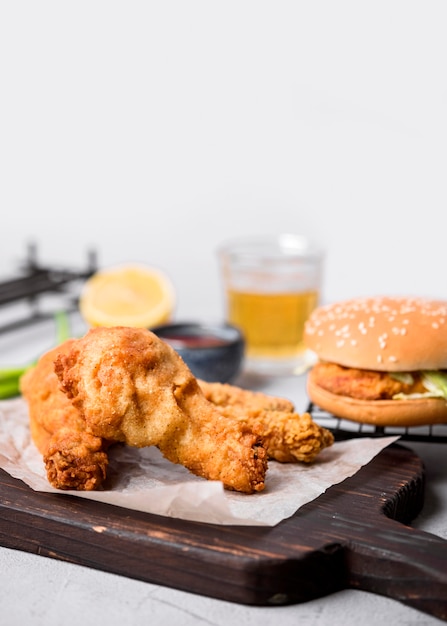 Vista frontal de pollo frito en tabla de cortar con hamburguesa