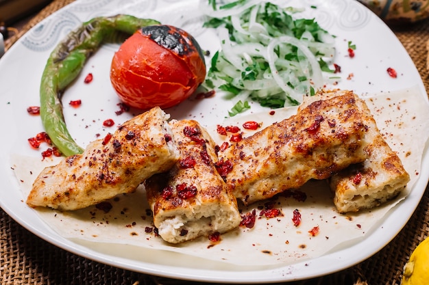 Vista frontal pollo lula kebab en pan de pita con tomate y pimiento asado con cebolla y hierbas