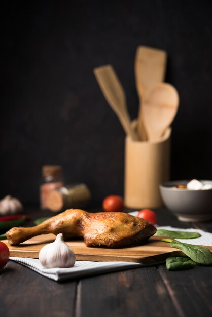 Vista frontal de pollo sobre tabla de madera con ingredientes