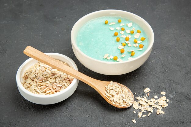 Vista frontal de postre helado azul con muesli crudo en el desayuno de cereales de frutas de mesa oscura