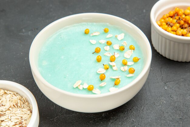 Vista frontal de postre helado azul con muesli crudo en el desayuno de cereales de frutas de mesa oscura