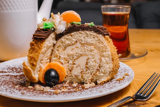 Vista frontal de postre pastel con rodajas de mandarina y un vaso de té