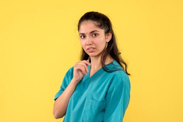 Vista frontal se preguntó bonita doctora de pie sobre fondo amarillo