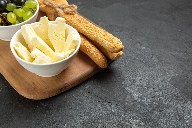 Vista frontal de queso blanco con uvas y pan sobre fondo oscuro, pan de leche, alimentos, fruta