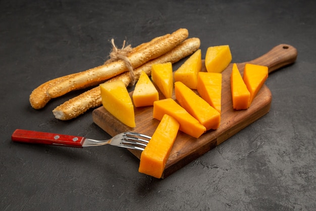 Vista frontal de queso fresco en rodajas con bollos sobre patatas fritas de desayuno de color oscuro de comida de aperitivo