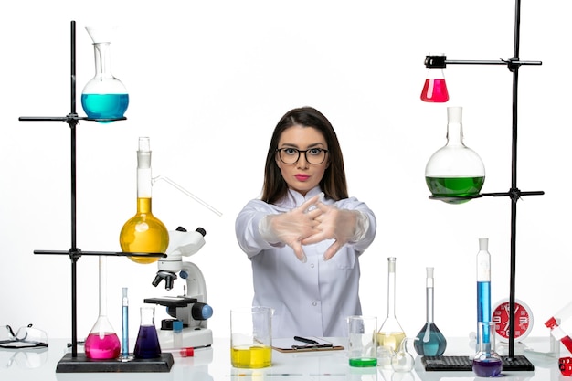 Vista frontal químico femenino en traje médico blanco preparándose para trabajar sobre fondo blanco laboratorio de pandemia de virus de ciencia covid