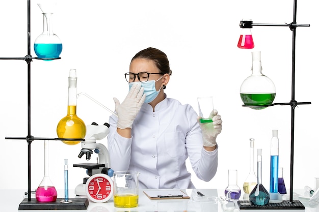 Foto gratuita vista frontal químico femenino en traje médico con máscara para beber solución sobre fondo blanco splash laboratorio virus química covid
