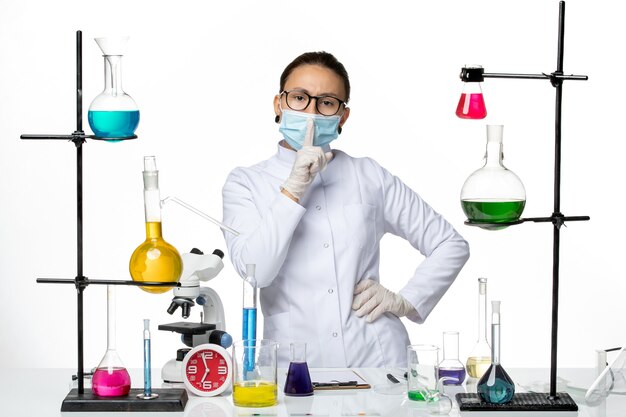Vista frontal químico femenino en traje médico con máscara de pie sobre fondo blanco claro laboratorio de química de virus covid- splash
