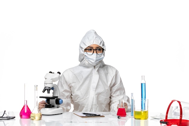 Vista frontal químico femenino en traje de protección especial sentado sobre fondo blanco química covid- virus de la salud
