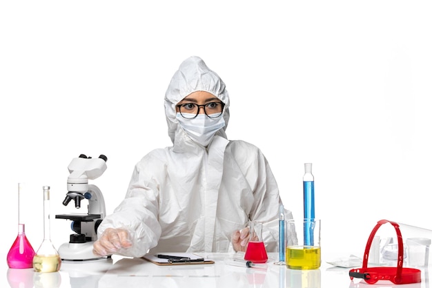 Vista frontal químico femenino en traje de protección especial sentado sobre fondo blanco química pandemia de virus covid