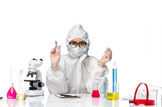 Vista frontal químico femenino en traje de protección especial sosteniendo la inyección sobre fondo blanco química pandemia de virus covid