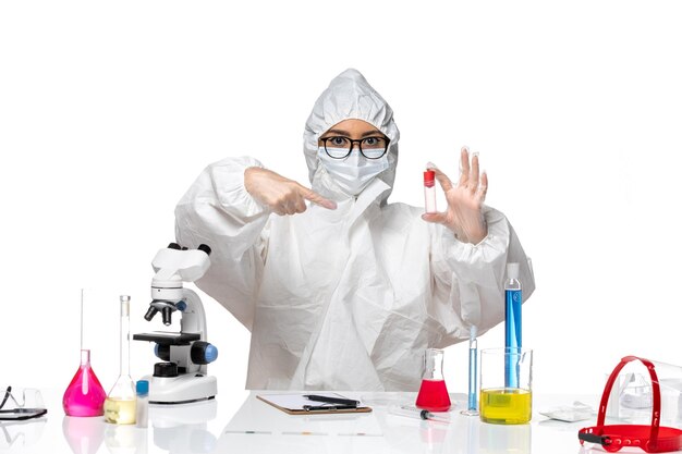 Vista frontal químico femenino en traje de protección especial sosteniendo el matraz sobre fondo blanco química de la salud del virus covid-