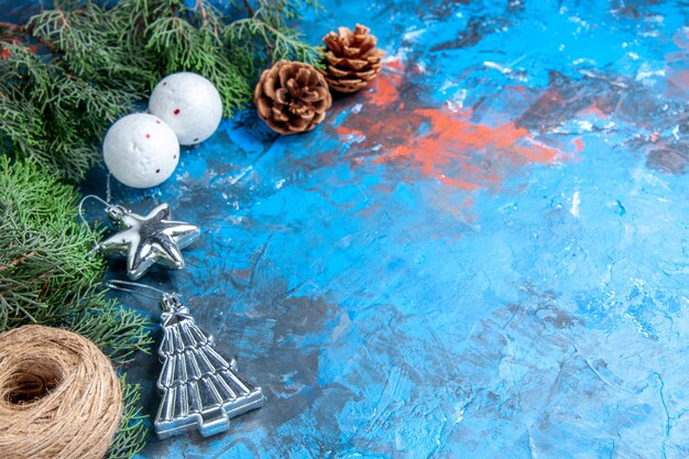 Vista frontal ramas de pino piñas bolas de árbol de navidad hilo de paja en azul-rojo con espacio libre
