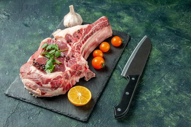 Vista frontal de la rebanada de carne fresca con tomates anaranjados en azul oscuro carne de comida animal de cocina color de pollo carnicero de vaca