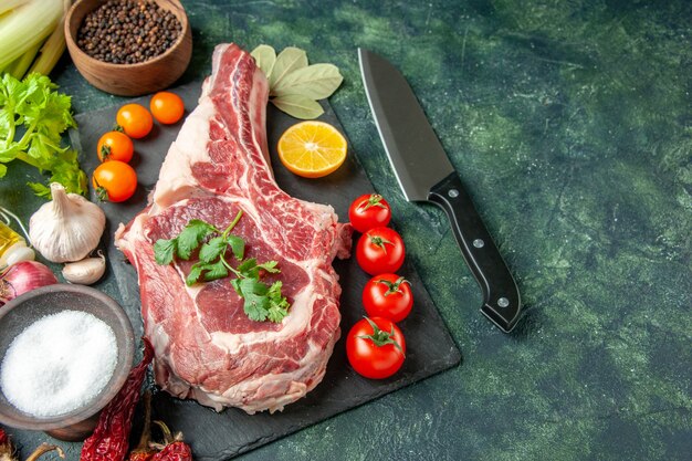 Vista frontal de la rebanada de carne fresca con tomates en un carnicero de vaca de color azul oscuro comida carne animal de cocina color pollo