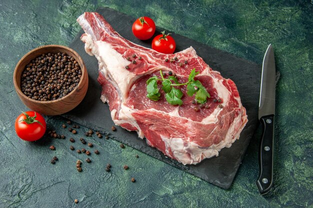 Vista frontal de la rebanada de carne fresca con tomates y pimiento en azul oscuro cocina animal vaca pollo color carne de carnicero