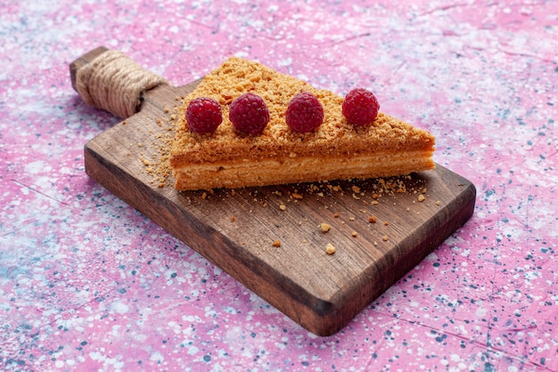 Vista frontal rebanada de pastel horneado y dulce con frambuesas en el escritorio de color rosa brillante hornear pastel dulce pastel de frutas