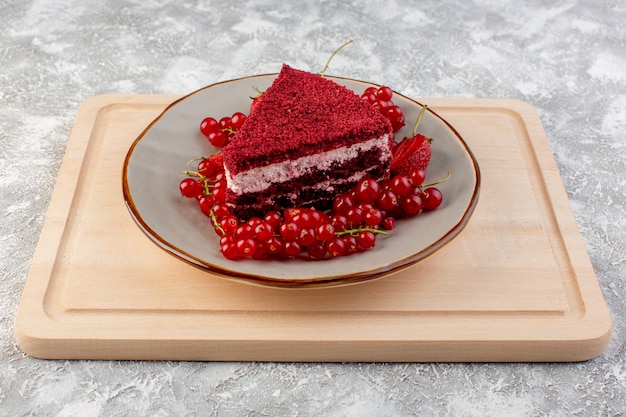 Vista frontal rebanada de pastel rojo pedazo de pastel de frutas dentro de la placa con arándanos frescos y fresas en té de escritorio de madera
