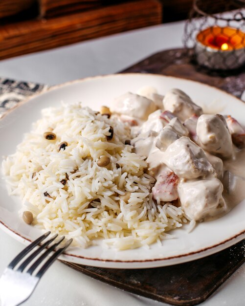 Vista frontal rebanadas de carne blanca junto con arroz y frijoles en el escritorio de madera marrón y piso claro