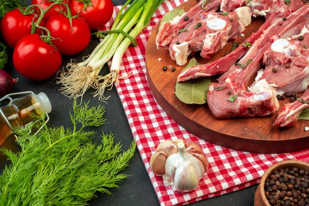 Vista frontal rebanadas de carne cruda con verduras frescas y verduras sobre fondo oscuro carnicero comida cena plato ensalada carne madura