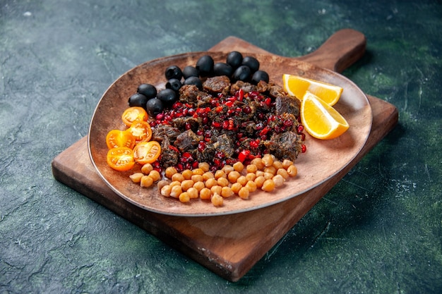 Vista frontal rebanadas de carne sabrosa comida frita con frutas dentro de la placa sobre fondo azul oscuro