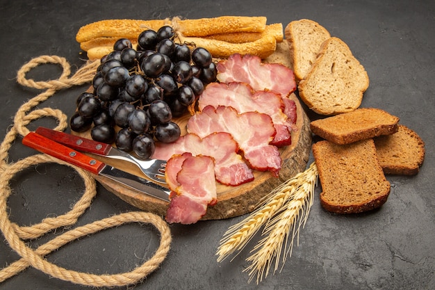 Foto gratuita vista frontal de las rebanadas de jamón con bollos y rebanadas de pan en la comida de comida de carne de bocadillo de foto en color oscuro