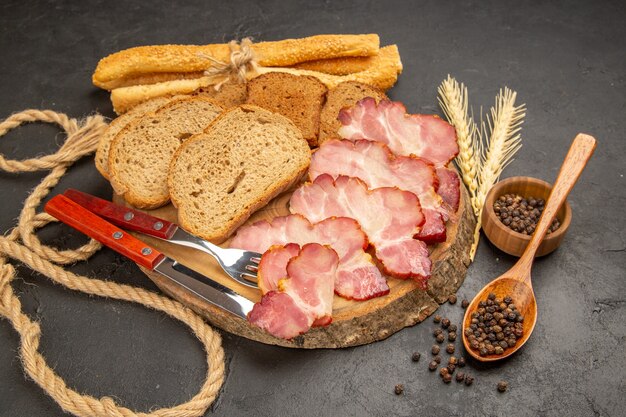 Vista frontal de las rebanadas de jamón fresco con bollos y rebanadas de pan en la comida de comida de carne de bocadillo de foto en color oscuro