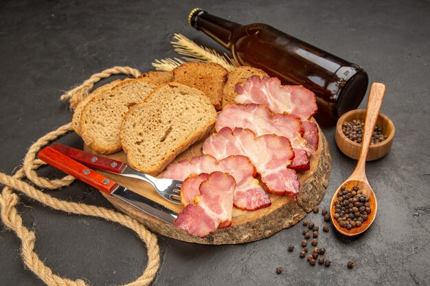 Vista frontal de las rebanadas de jamón fresco con botella y rebanadas de pan en la comida oscura de la comida del color de la carne del bocado de la foto