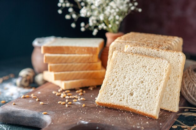 Vista frontal de rebanadas de pan blanco sobre fondo oscuro bollo de masa de panadería alimentos desayuno hogaza mañana pastelería