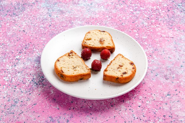 Vista frontal de las rebanadas de pastel con fresas dentro de la placa en la superficie rosa pastel hornear galletas dulces en color de azúcar