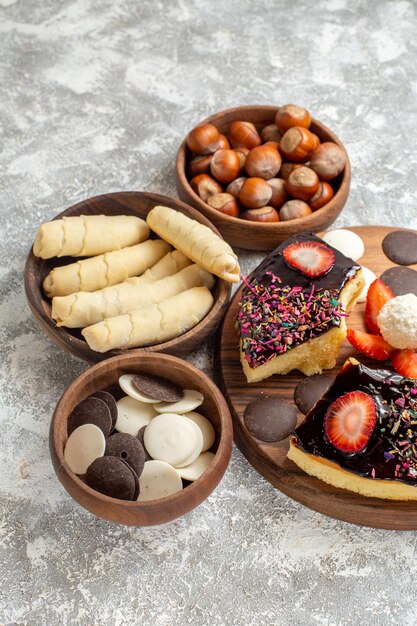 Vista frontal de las rebanadas de pastel con galletas, nueces y dulces sobre fondo blanco.