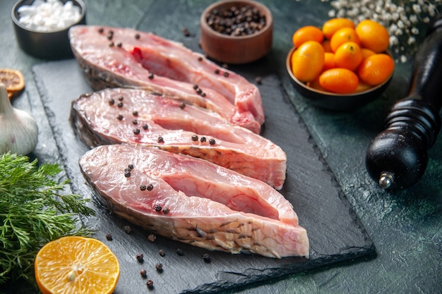 Vista frontal rebanadas de pescado fresco con pimienta sobre una superficie oscura carne comida cruda foto de agua marisco del océano cena de color