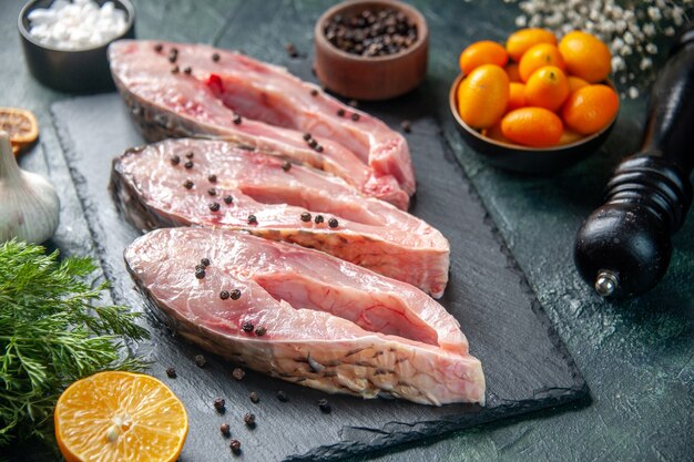 Vista frontal rebanadas de pescado fresco con pimienta sobre una superficie oscura carne comida cruda foto de agua marisco del océano cena de color