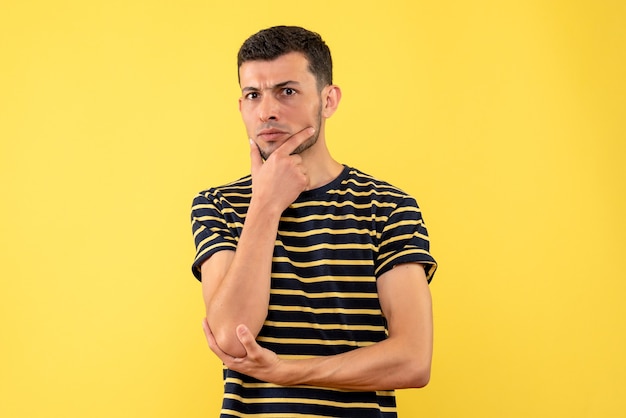 Vista frontal reflexivo hombre guapo en camiseta a rayas blanco y negro fondo amarillo aislado