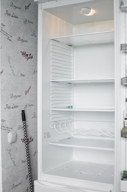 Vista frontal del refrigerador vacío que se queda en casa Congelador moderno blanco sin alimentos verduras y frutas en casa Refrigerador eléctrico con varios estantes Concepto de electrodoméstico y enfriador