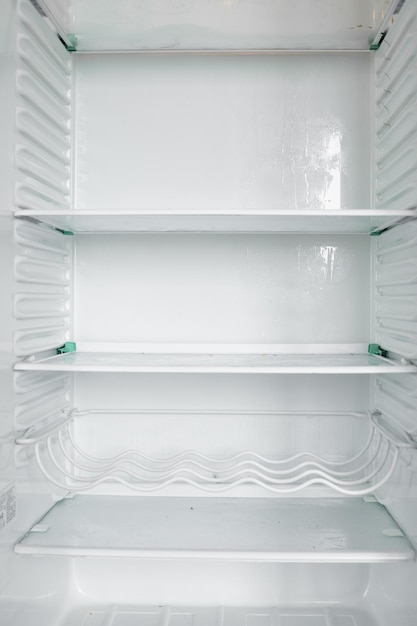 Vista frontal del refrigerador vacío que se queda en casa Congelador moderno blanco sin alimentos verduras y frutas en casa Refrigerador eléctrico con varios estantes Concepto de electrodoméstico y enfriador