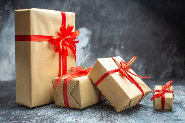 Vista frontal de regalos de navidad atados con lazos rojos en el color claro-oscuro regalo de navidad de año nuevo